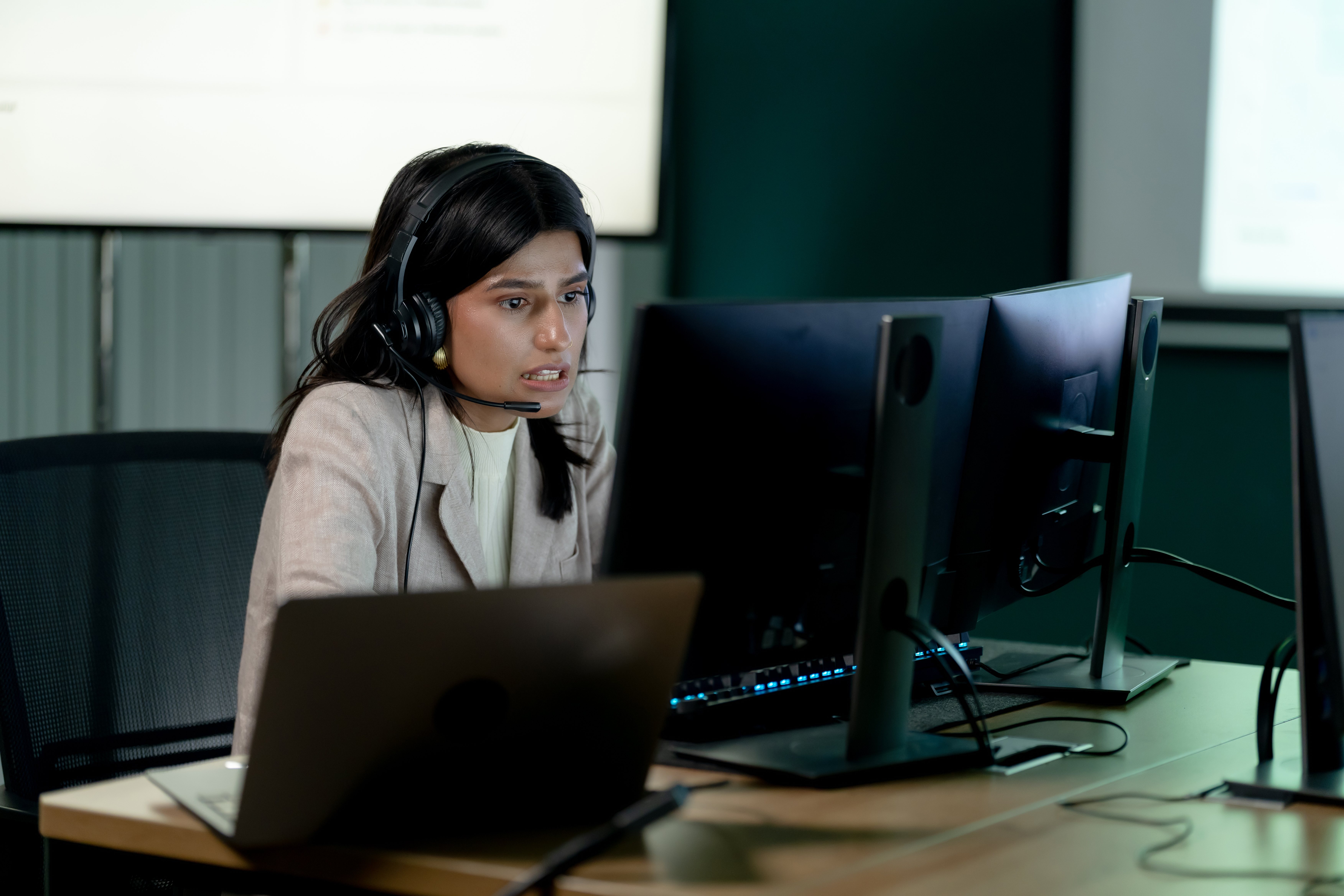 Adult female call center agent works at computer with headset in modern office, handling customer support requests, online communication, technical assistance, and professional service workflow.